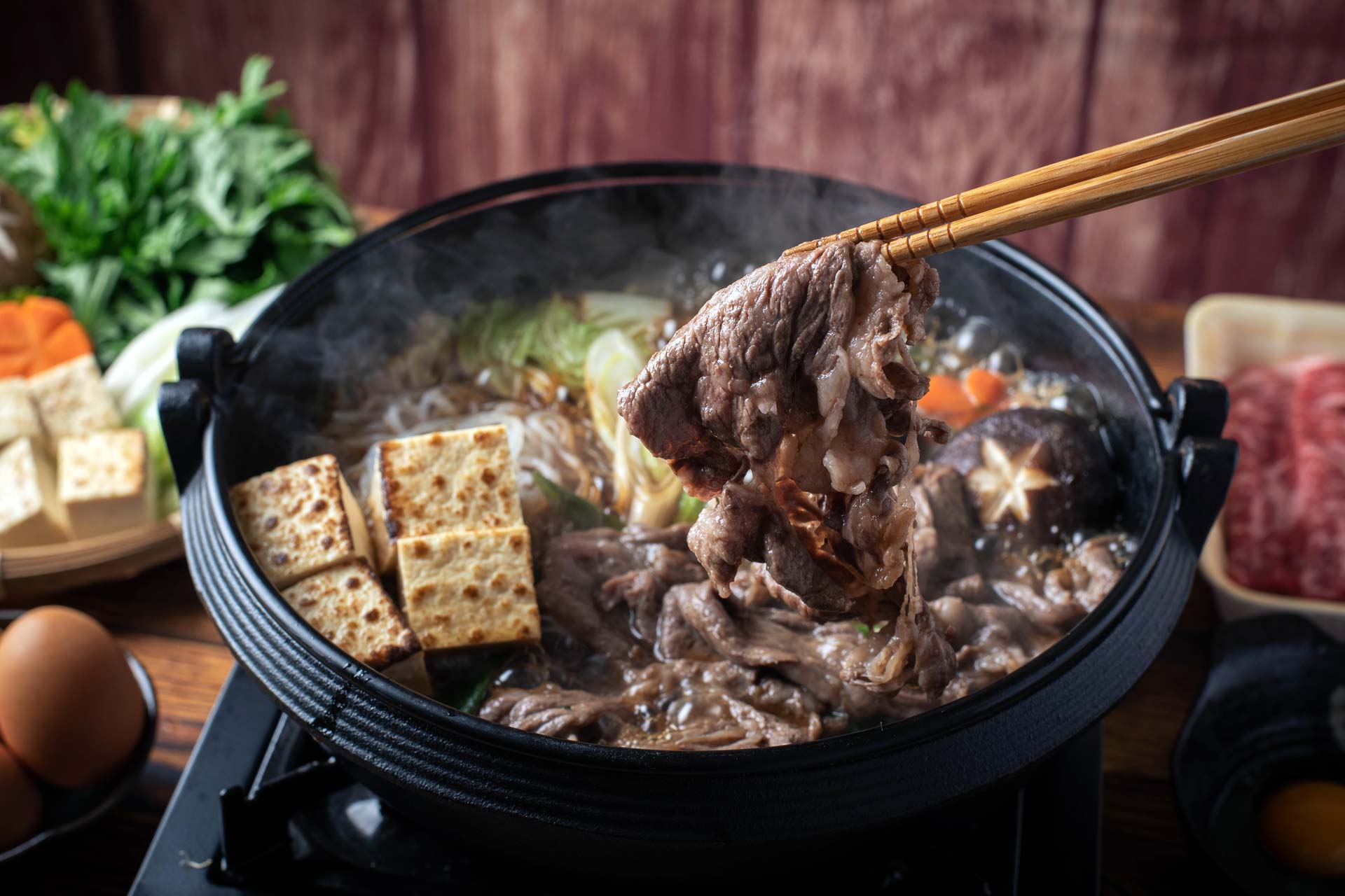 Chopsticks picking up cooked beef out of a bowl of soup